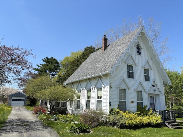 20 Westbrook St, South Thomaston, ME 04858 - view of front facade with asphalt driveway, a chimney, an outbuilding, a shingled roof, and a garage