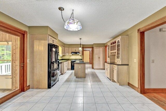 kitchen featuring a center island, freestanding refrigerator, dark countertops, under cabinet range hood, and electric range oven