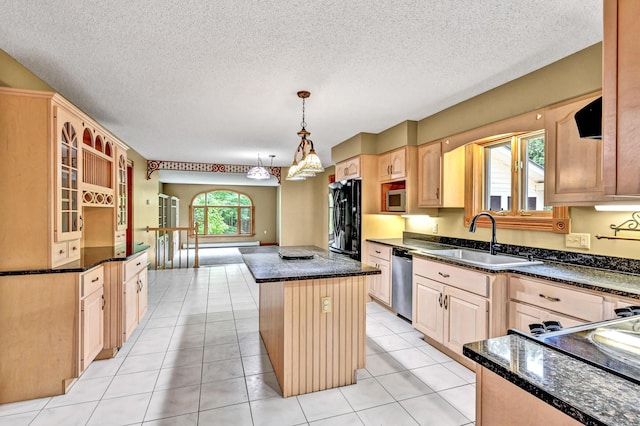 kitchen featuring light tile patterned floors, light brown cabinetry, a center island, a sink, and stainless steel appliances