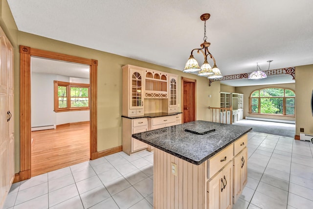 kitchen with a center island, glass insert cabinets, a baseboard heating unit, and light tile patterned flooring