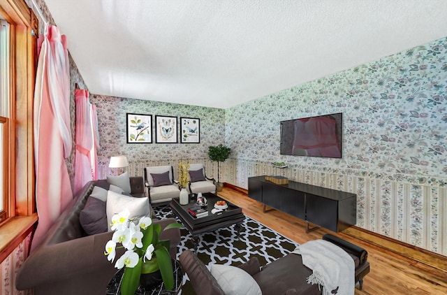 living room with a textured ceiling, wallpapered walls, and wood finished floors