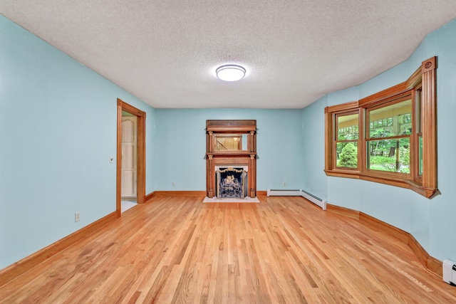 unfurnished living room featuring a fireplace with flush hearth, a textured ceiling, baseboard heating, wood finished floors, and baseboards