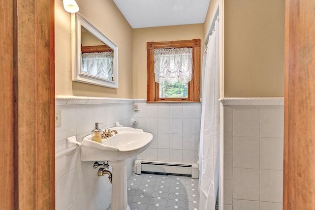 full bathroom with a baseboard heating unit, tile patterned flooring, a shower with curtain, a wainscoted wall, and tile walls