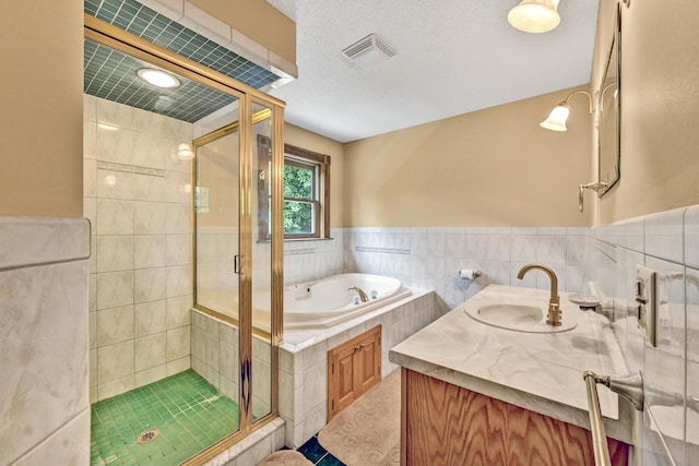 bathroom with a shower stall, visible vents, a textured ceiling, and a garden tub