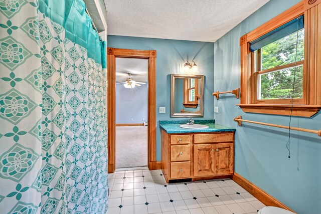 bathroom with a shower with shower curtain, vanity, a textured ceiling, and baseboards