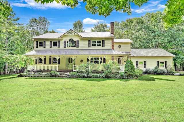 view of front facade with a porch, a chimney, metal roof, and a front yard