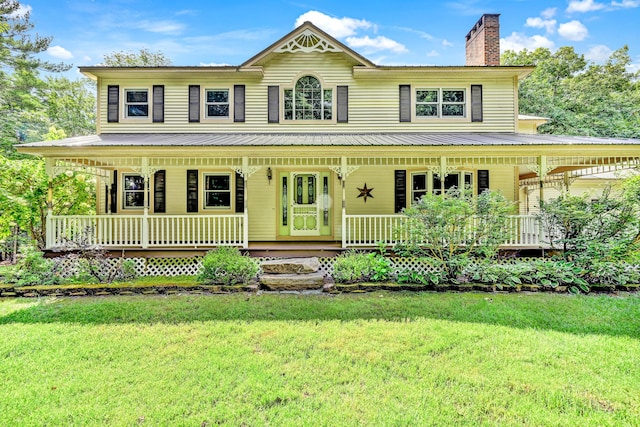 view of front of property with a front yard, a chimney, and covered porch
