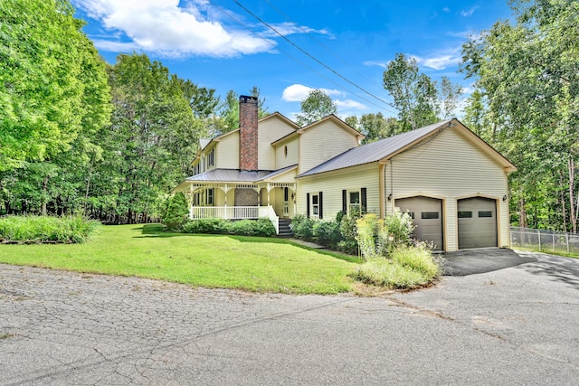 view of front of home with a porch, driveway, a chimney, and a front lawn