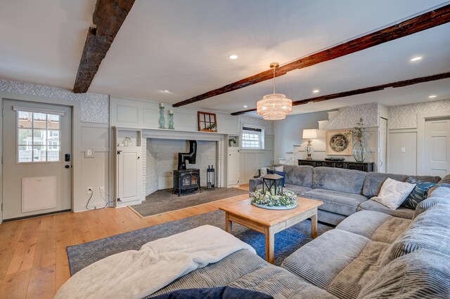 917 Main St, Fryeburg, ME 04037 - living area featuring a wood stove, light wood-style flooring, stairs, beam ceiling, and a decorative wall