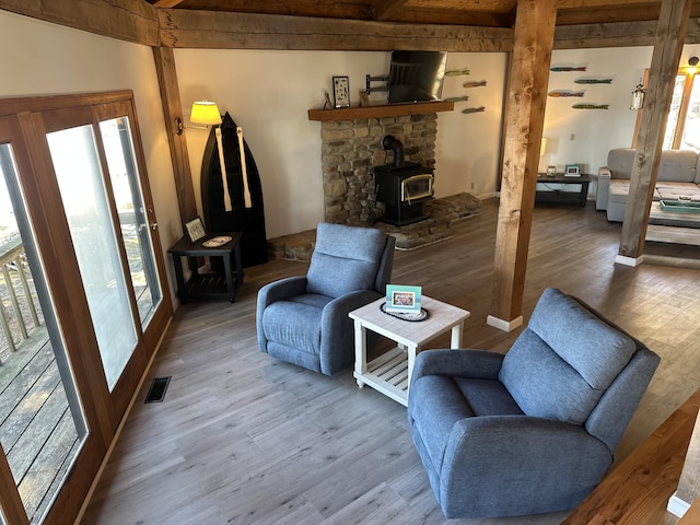 93 Goods Point Rd, Steuben, ME 04680 - living room with beamed ceiling, a wood stove, visible vents, and wood finished floors
