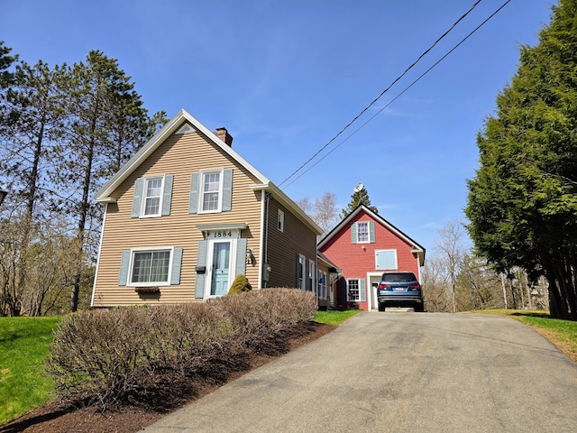 traditional-style house featuring driveway and a chimney