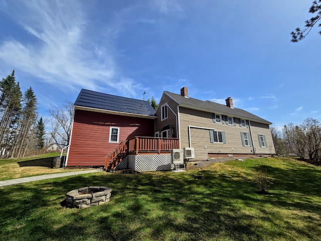 rear view of house featuring a fire pit, a deck, a chimney, a yard, and stairway