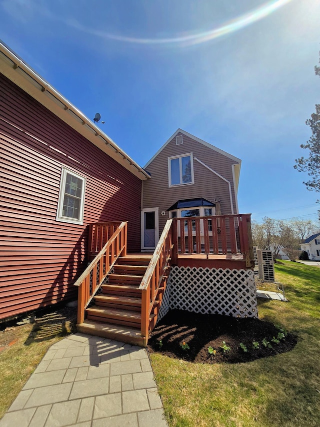 rear view of property featuring a yard, a deck, and stairway
