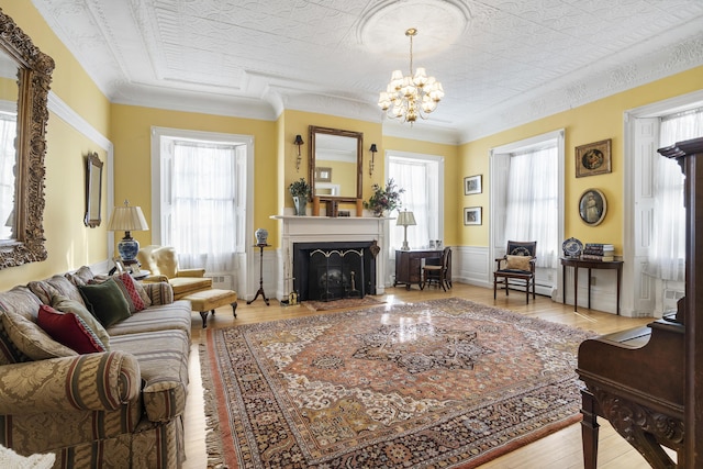 103 S St, Bath, ME 04530 - living room featuring a baseboard heating unit, light wood-style floors, a fireplace, a notable chandelier, and ornamental molding