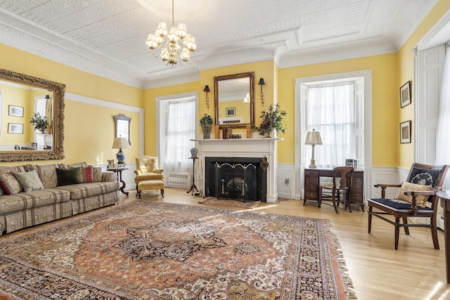 103 S St, Bath, ME 04530 - living area with wood finished floors, a chandelier, a wainscoted wall, a fireplace with flush hearth, and crown molding