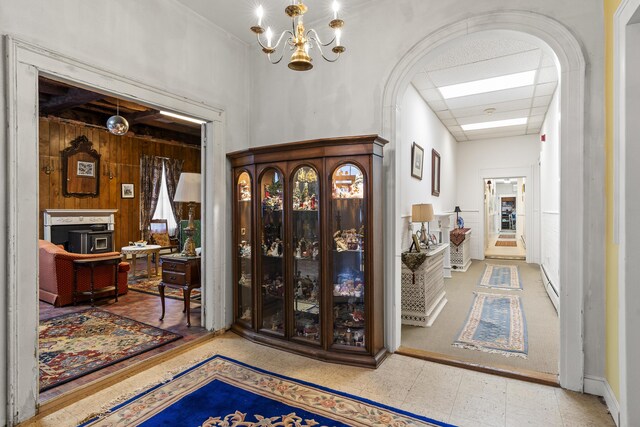 103 S St, Bath, ME 04530 - foyer with a baseboard radiator, arched walkways, an inviting chandelier, wooden walls, and a drop ceiling