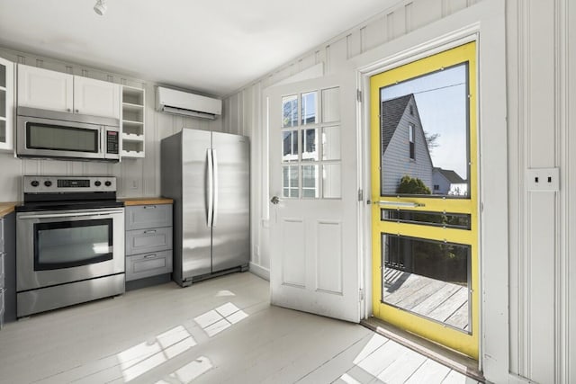 9 School St, Boothbay Harbor, ME 04538 - kitchen featuring glass insert cabinets, open shelves, white cabinetry, stainless steel appliances, and a wall mounted air conditioner