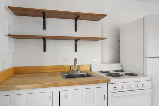 9 School St, Boothbay Harbor, ME 04538 - kitchen featuring wood counters, open shelves, white cabinets, white electric range, and a sink