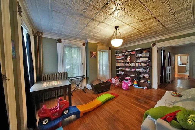 84 Military St, Houlton, ME 04730 - living area with crown molding, radiator heating unit, an ornate ceiling, and wood finished floors