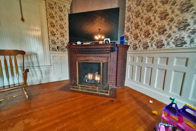 84 Military St, Houlton, ME 04730 - detailed view of wallpapered walls, wainscoting, a decorative wall, a brick fireplace, and wood finished floors