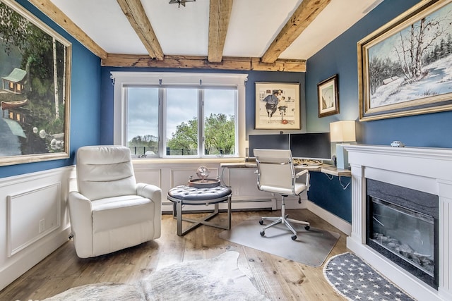sitting room with a wainscoted wall, beamed ceiling, a baseboard radiator, and hardwood / wood-style floors