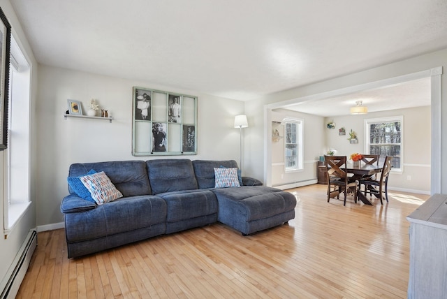 living room featuring baseboards, light wood finished floors, and a baseboard heating unit