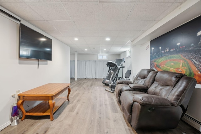 living area featuring baseboards, recessed lighting, a baseboard radiator, a drop ceiling, and wood finished floors