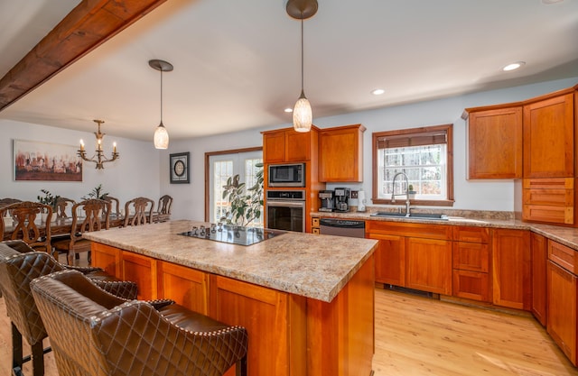 575 Hallowell Rd, Chelsea, ME 04330 - kitchen featuring stainless steel appliances, a sink, a kitchen island, light wood finished floors, and brown cabinetry