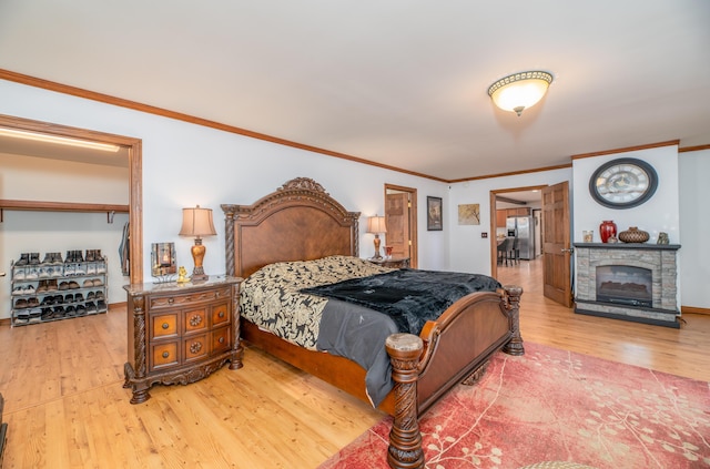 575 Hallowell Rd, Chelsea, ME 04330 - bedroom featuring wood finished floors, ornamental molding, stainless steel refrigerator with ice dispenser, a stone fireplace, and baseboards