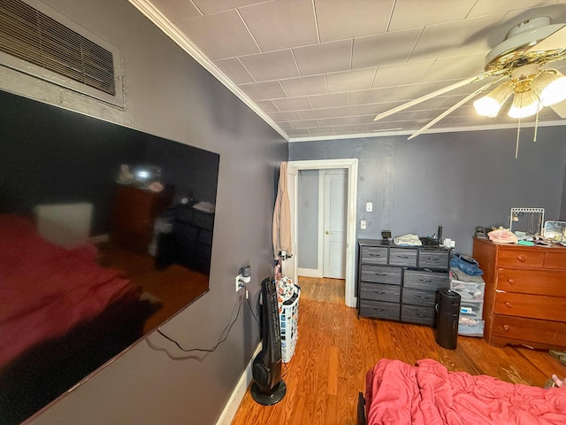 bedroom with visible vents, baseboards, crown molding, and wood finished floors
