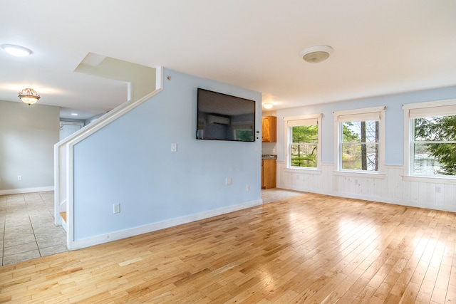 480 E Shore Dr, Acton, ME 04001 - unfurnished living room with baseboards, a wealth of natural light, light wood-style floors, and wainscoting