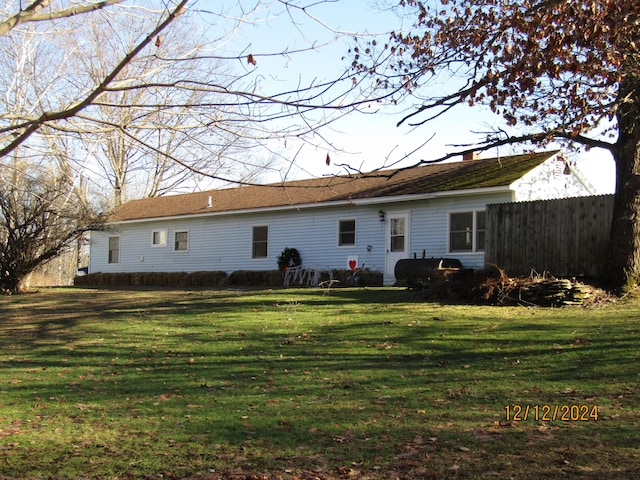 rear view of property featuring fence, a lawn, and a chimney