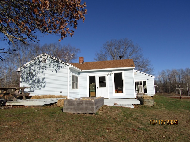 back of property with roof with shingles, a lawn, and a chimney
