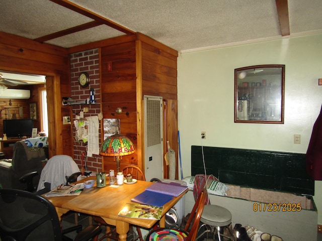 dining area featuring a textured ceiling, wooden walls, and beam ceiling