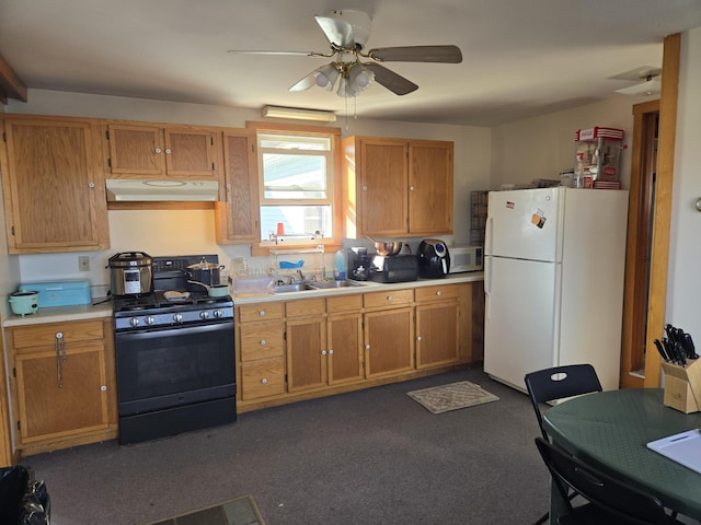 kitchen featuring freestanding refrigerator, under cabinet range hood, gas stove, a sink, and light countertops