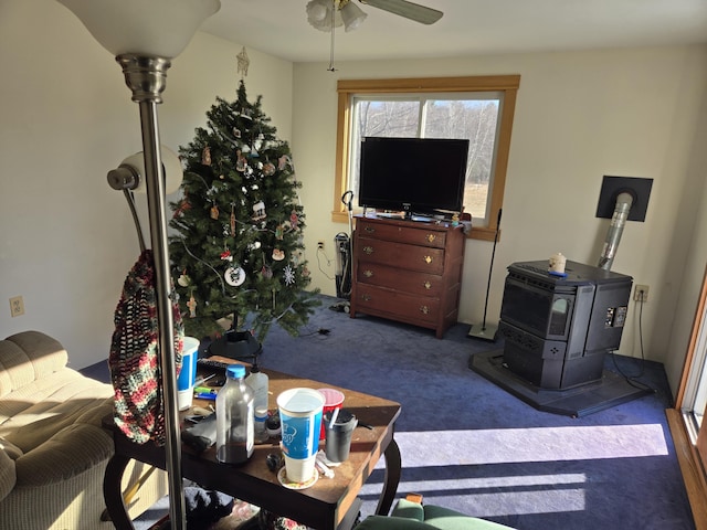 living room featuring a wood stove, carpet flooring, and a ceiling fan