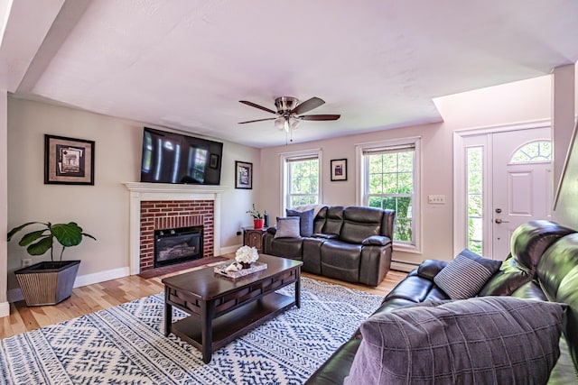 18 Sheila Cir, Saco, ME 04072 - living room featuring a ceiling fan, light wood-style floors, baseboard heating, baseboards, and a brick fireplace