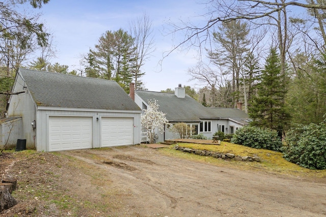 12 Bufflehead Cove Ln, Kennebunk, ME 04043 - view of front facade with a chimney, dirt driveway, roof with shingles, and central AC