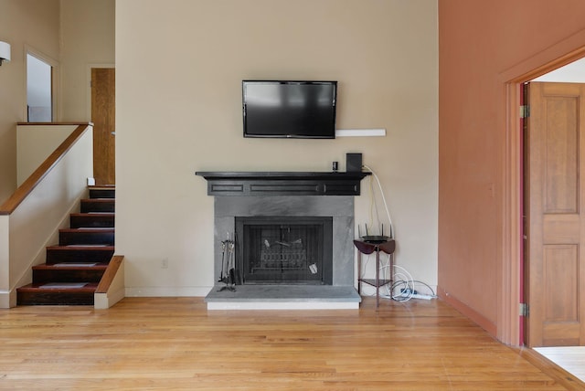 12 Bufflehead Cove Ln, Kennebunk, ME 04043 - unfurnished living room with baseboards, stairs, a fireplace with raised hearth, and wood finished floors