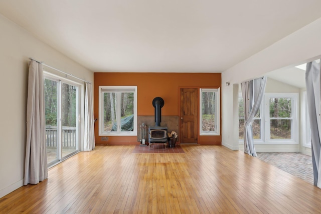 12 Bufflehead Cove Ln, Kennebunk, ME 04043 - unfurnished living room featuring baseboards, a wealth of natural light, a wood stove, and wood-type flooring