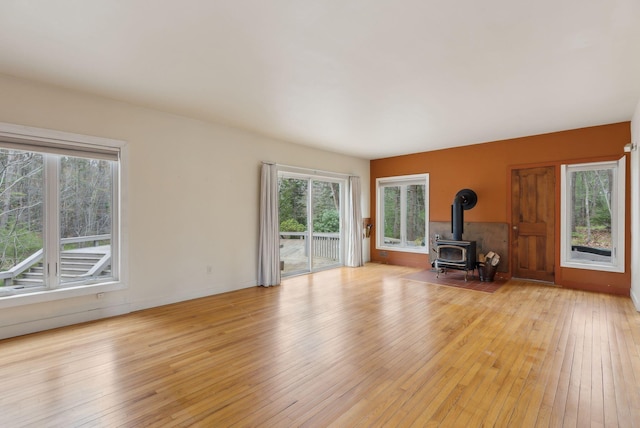 12 Bufflehead Cove Ln, Kennebunk, ME 04043 - unfurnished living room with a wood stove, a wealth of natural light, and light wood-type flooring