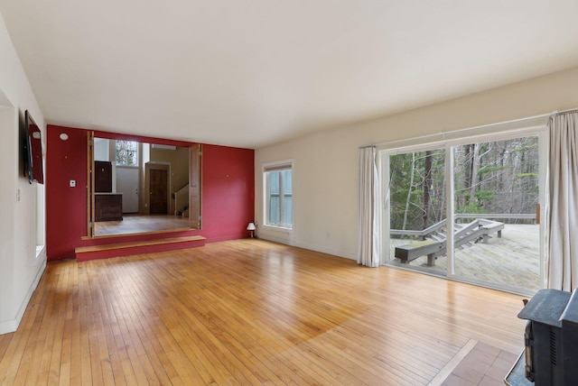 12 Bufflehead Cove Ln, Kennebunk, ME 04043 - unfurnished living room with baseboards, a wood stove, and light wood-style flooring