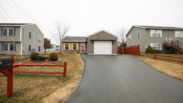 view of front of home featuring a front lawn, fence, a garage, and aphalt driveway