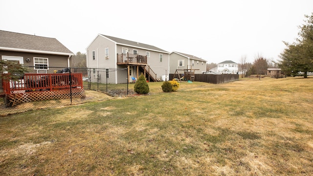 back of property featuring fence, a deck, a residential view, and a lawn