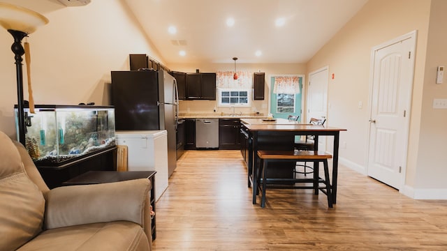 kitchen featuring vaulted ceiling, light wood-style flooring, light countertops, stainless steel appliances, and a sink
