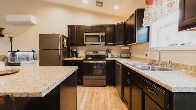kitchen featuring visible vents, appliances with stainless steel finishes, a sink, an AC wall unit, and lofted ceiling