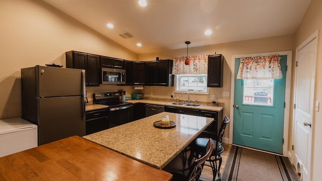 kitchen with freestanding refrigerator, visible vents, stainless steel microwave, a sink, and range with electric cooktop