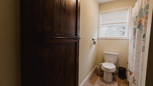 full bathroom featuring toilet and baseboards