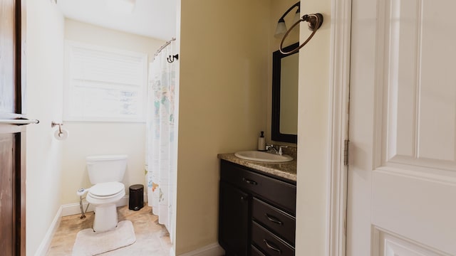 bathroom with tile patterned flooring, vanity, baseboards, and toilet