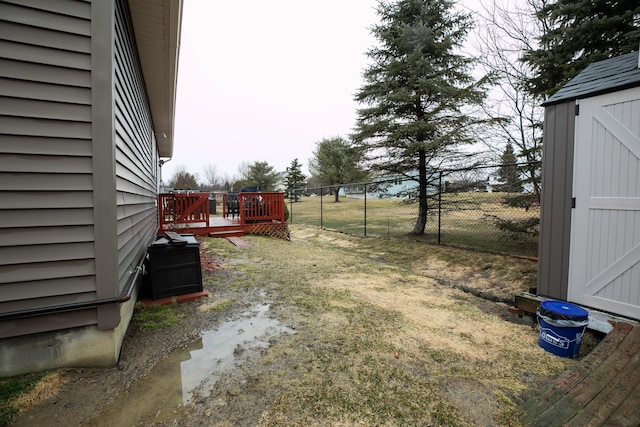 view of yard with a wooden deck, fence, an outbuilding, and a storage unit